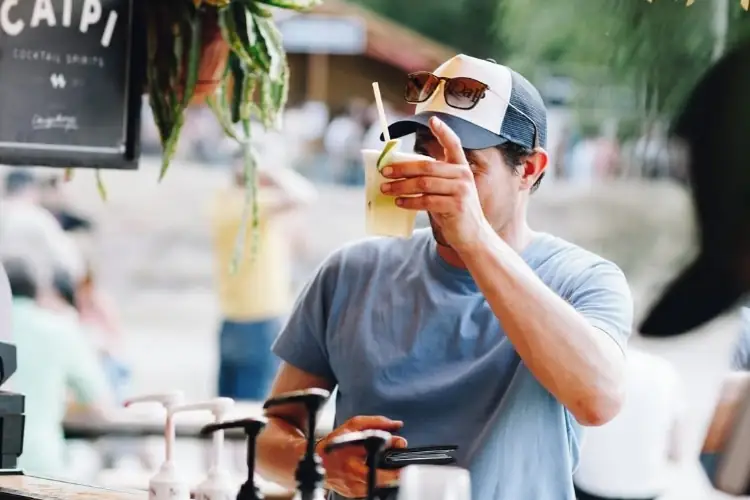 Een gast die proost met een drankje in de zon