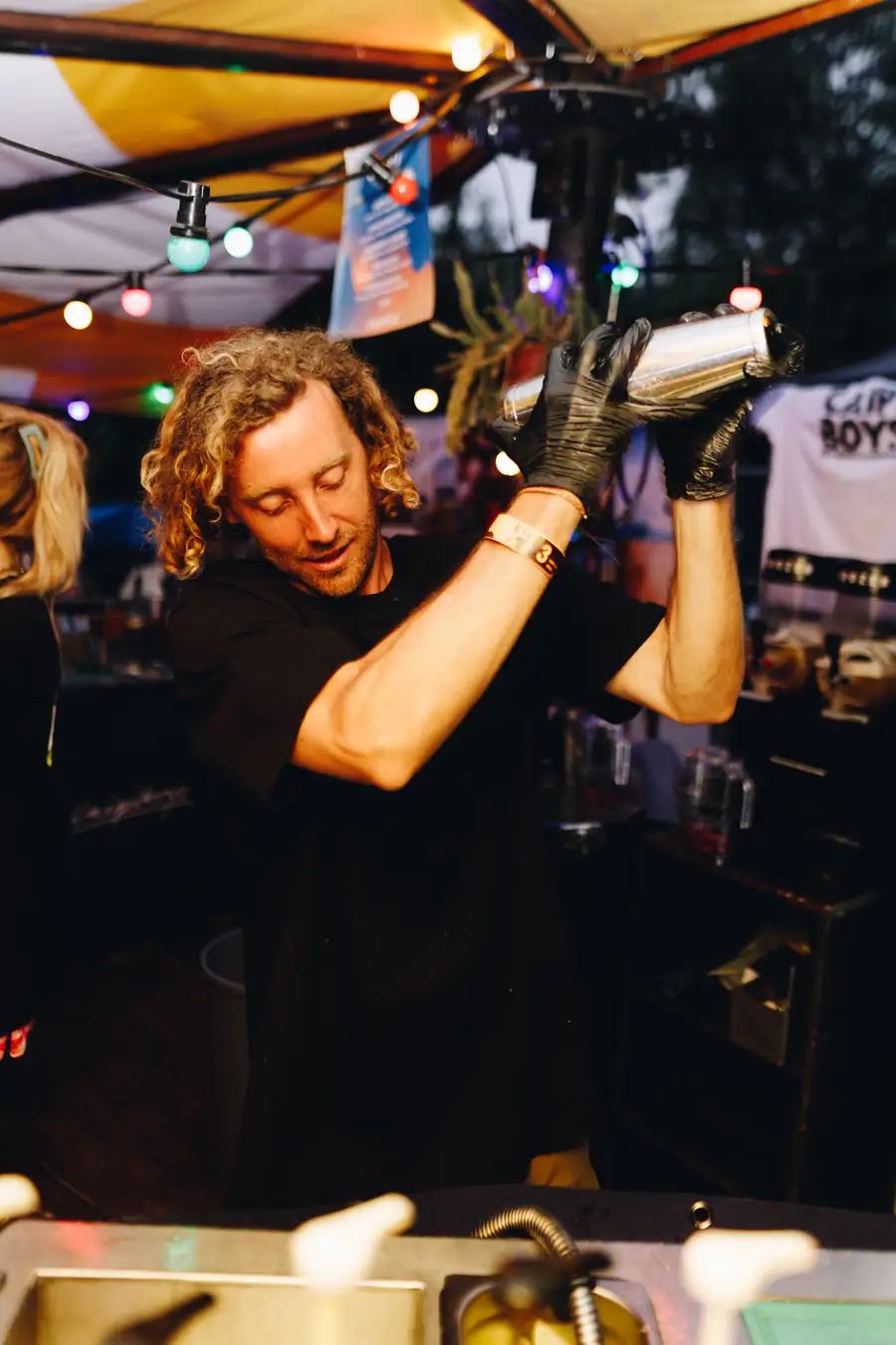 Een bartender van Caipi achter een mobiele cocktailbar op een festival, met een shaker in de hand
