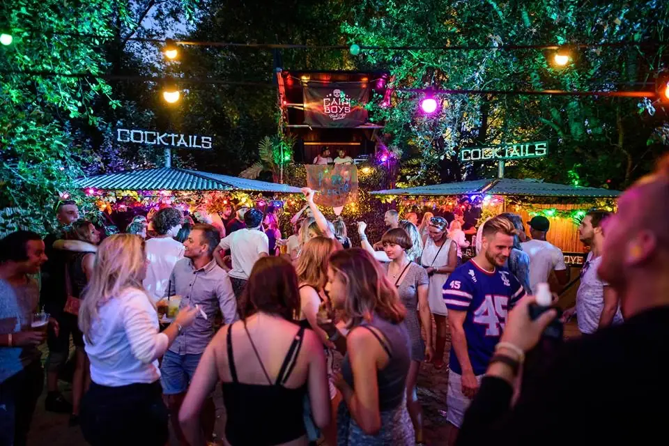 Een feestende menigte bij een Caipi-cocktailbar onder gekleurde lampen