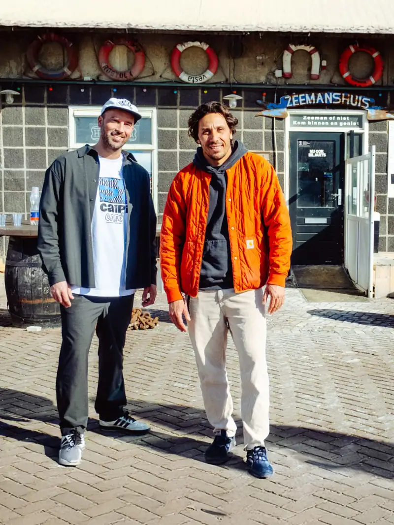 Twee mannen voor de blauwe voordeur van het Zeemanshuis, met rode reddingsbanden boven de deur