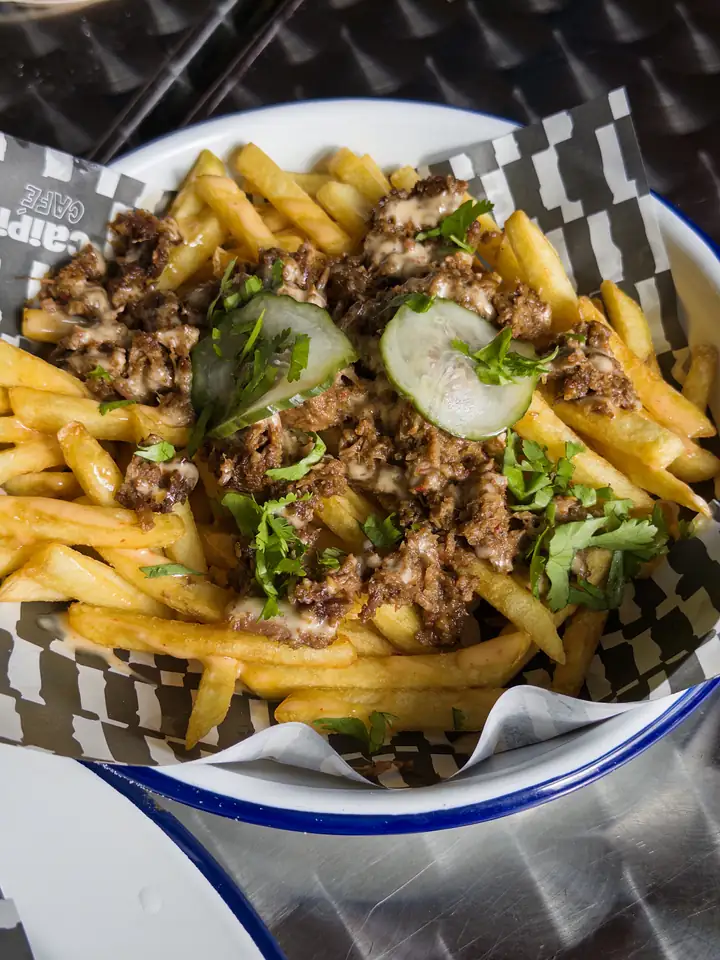 Loaded fries in een mandje met blauw-wit geblokte bakpapier