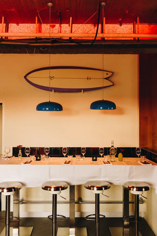 De zaal met de lange bar, barkrukken en een surfboard aan de wand