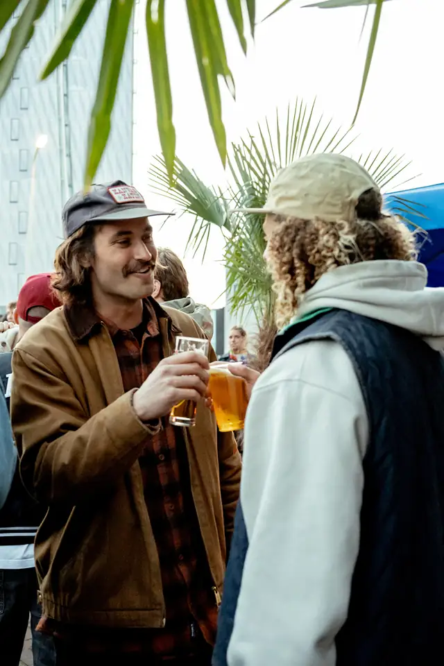Twee gasten die lachend een biertje drinken op het terras