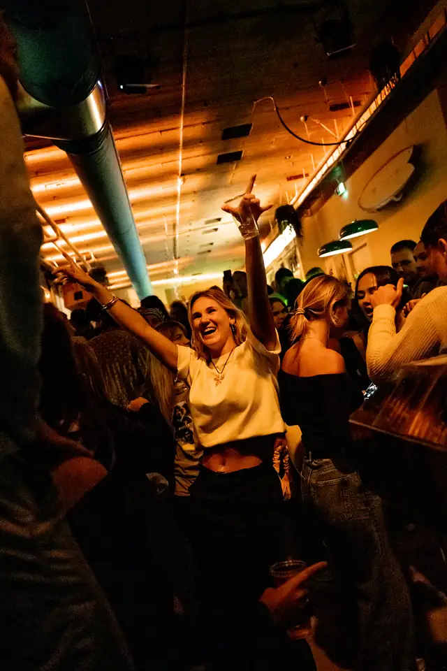 Een volle zaal gasten die dansen en proosten bij Caipi Café
